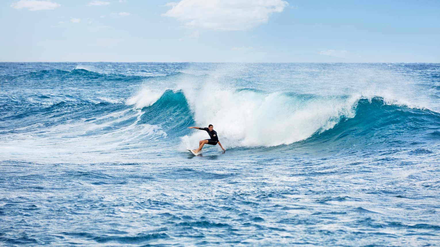 Surfer in black wetsuit rides high wave