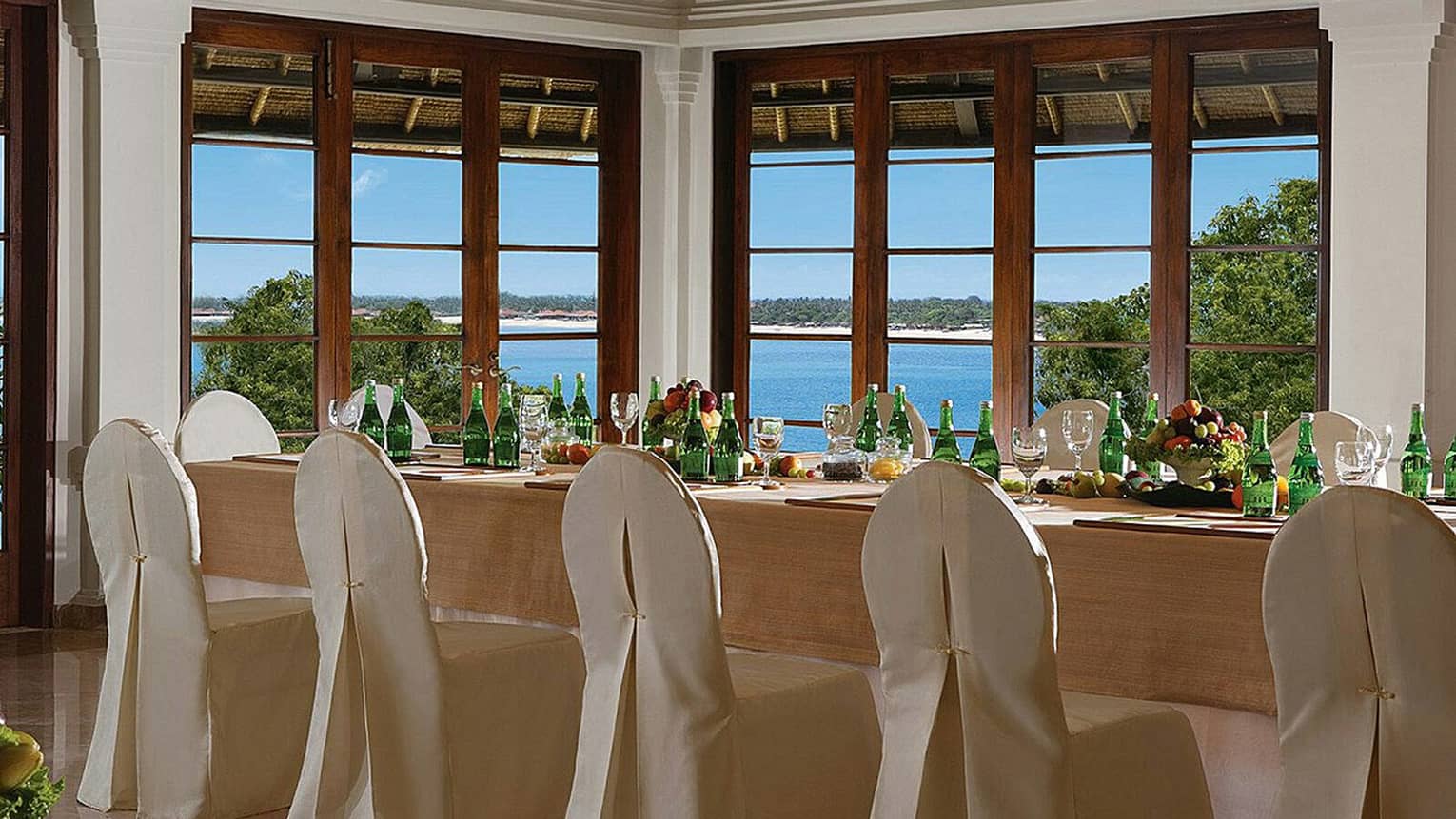 Jepun Sari king banquet table with silk covered chairs by corner windows