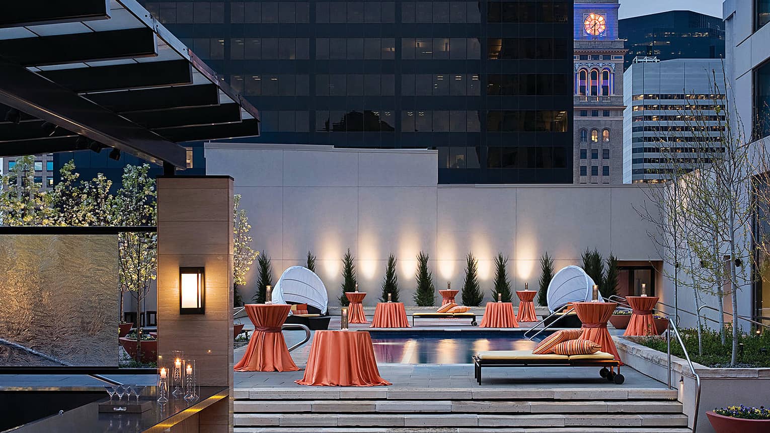 Cocktail tables with red linens on event terrace with bar, small swimming pool 