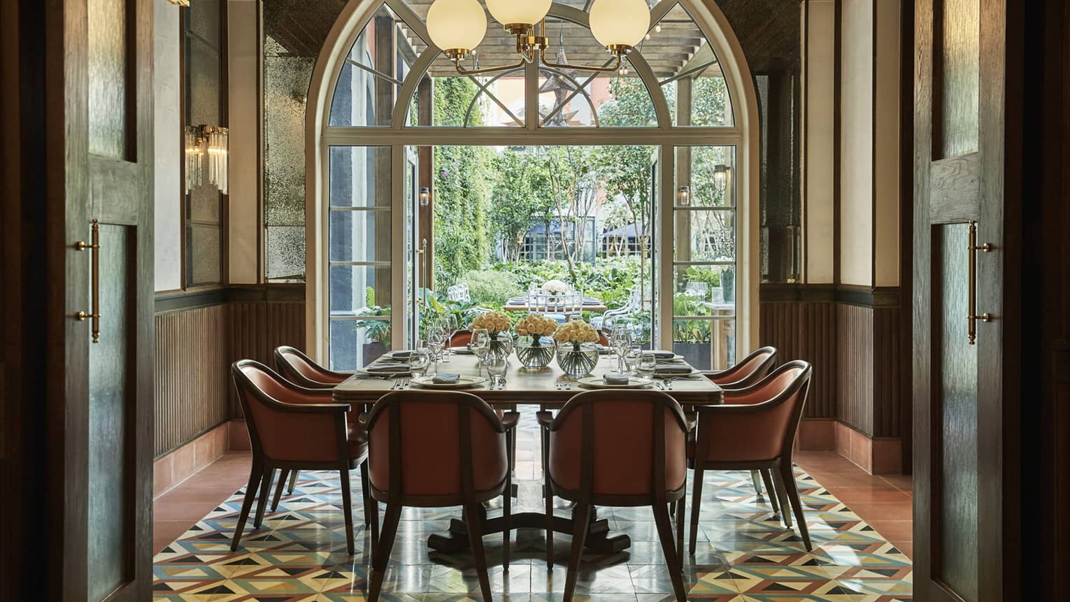 Private dining table under sunny arched window, globe lights 