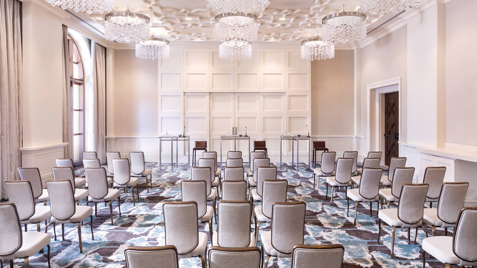 Sunny conference room with rows of chairs facing three speaker tables