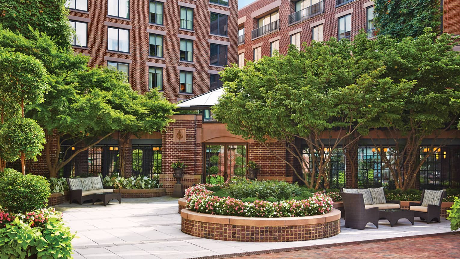 Hotel courtyard with trees, large garden planters, patio furniture