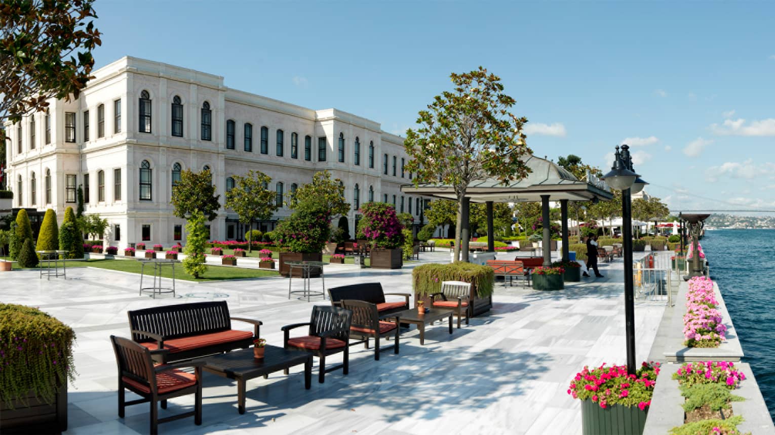 Lounge seating areas on large, sunny hotel outdoor event patio on water 