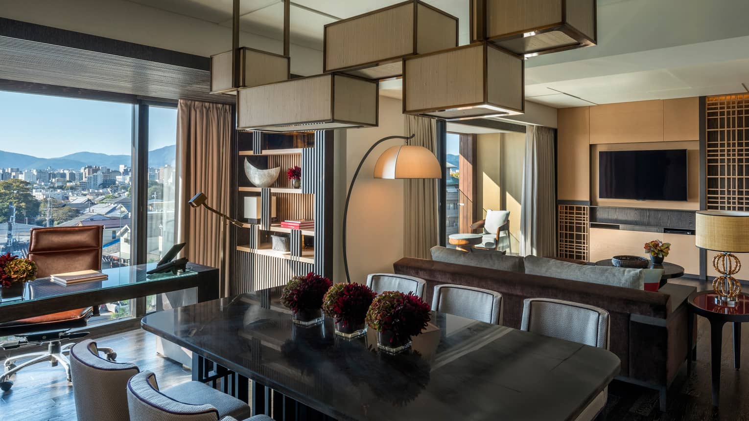 Executive desk, dining table under chandelier by back of sofa, living room