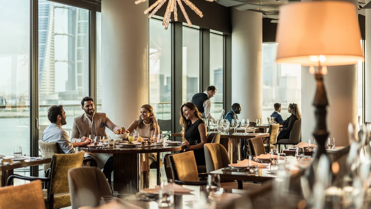 Smiling groups of friends at dining tables by window in lounge 
