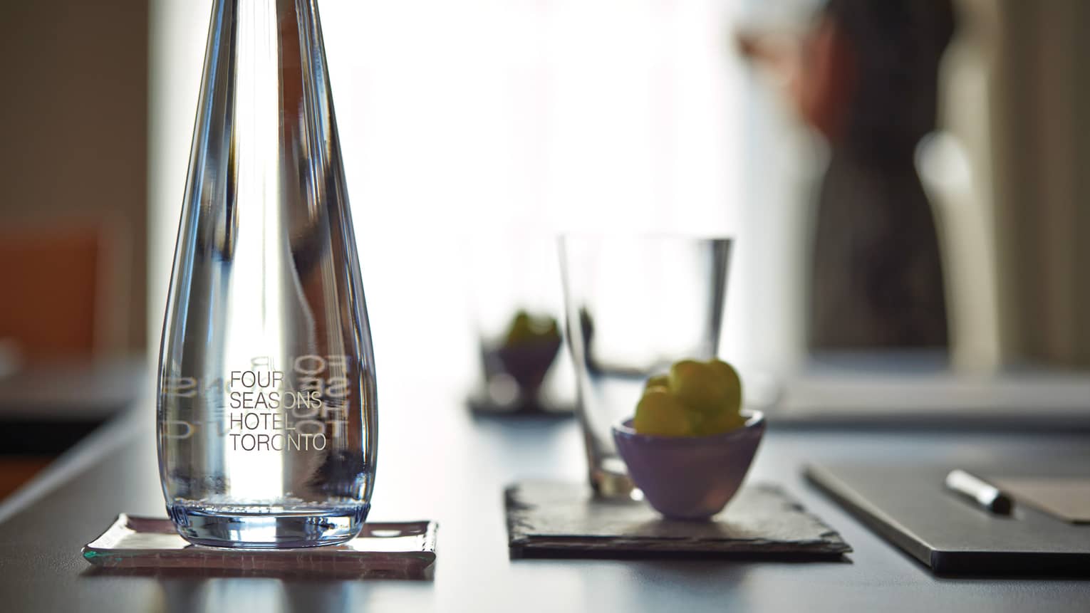 Close-up of glass water bottle, cup and agenda on meeting table