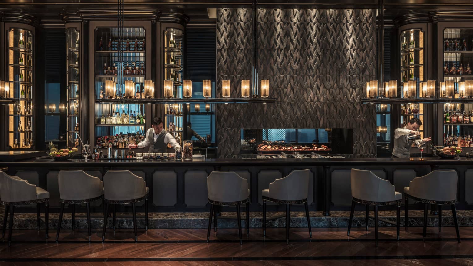 Gusto bartender reaches for jar behind long bar under liquor display, lanterns