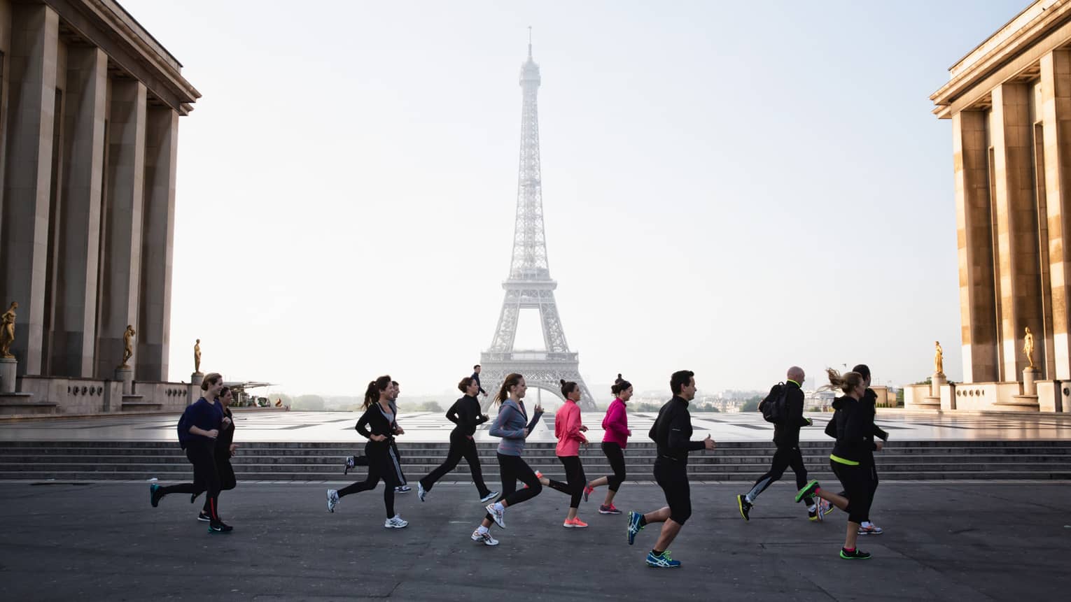 Group of people jogging along pavement with Eiffel Tower in background 