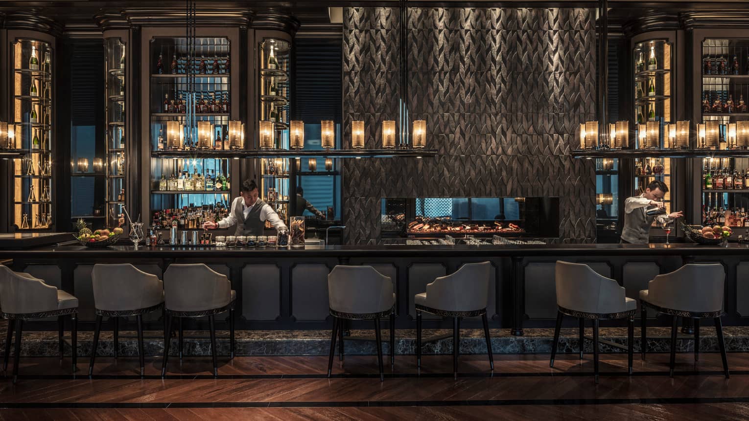 Gusto bartender reaches for jar behind long bar under liquor display, lanterns