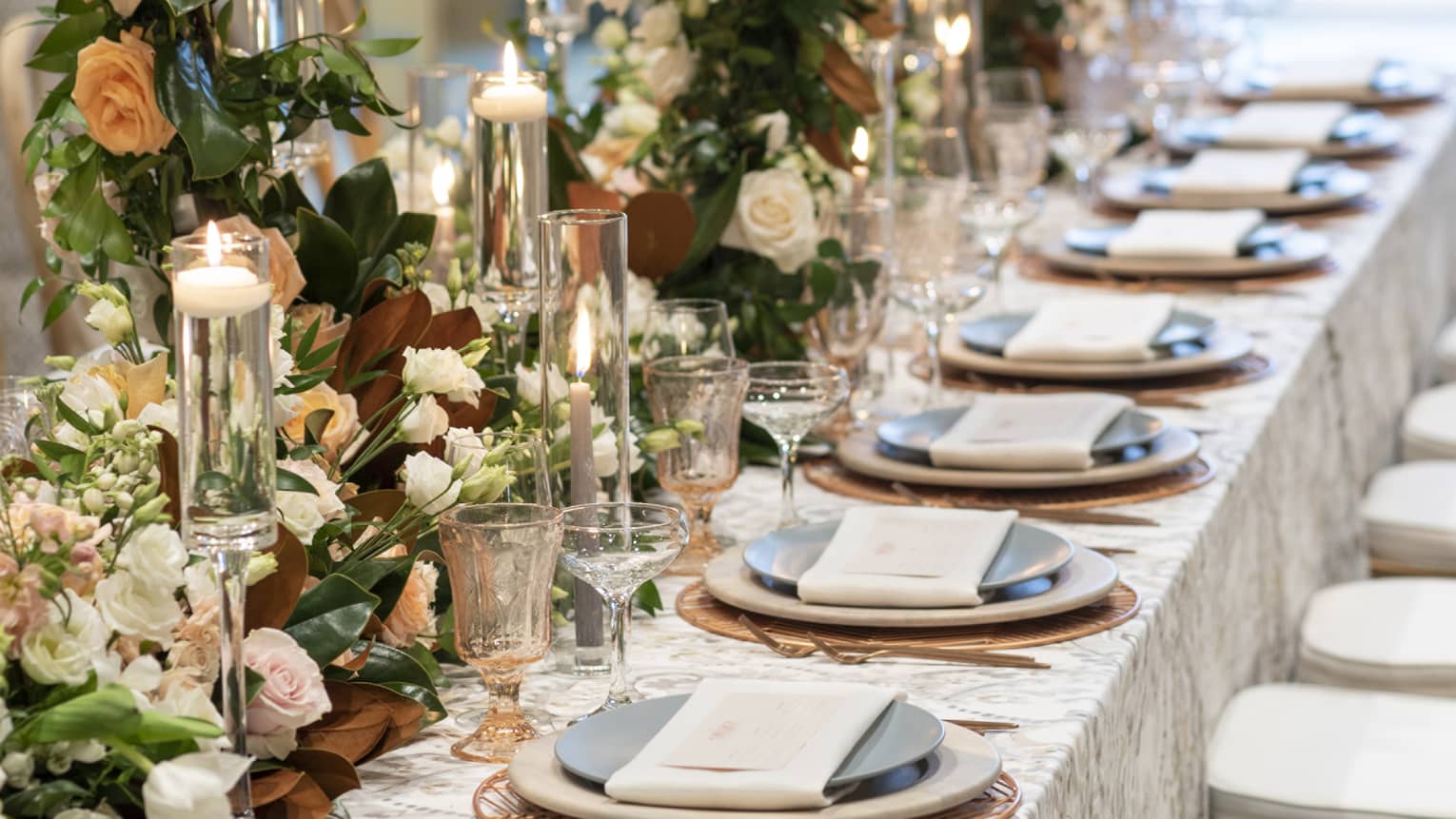 Long wedding dining table with floral wreath centrepiece by sunny window