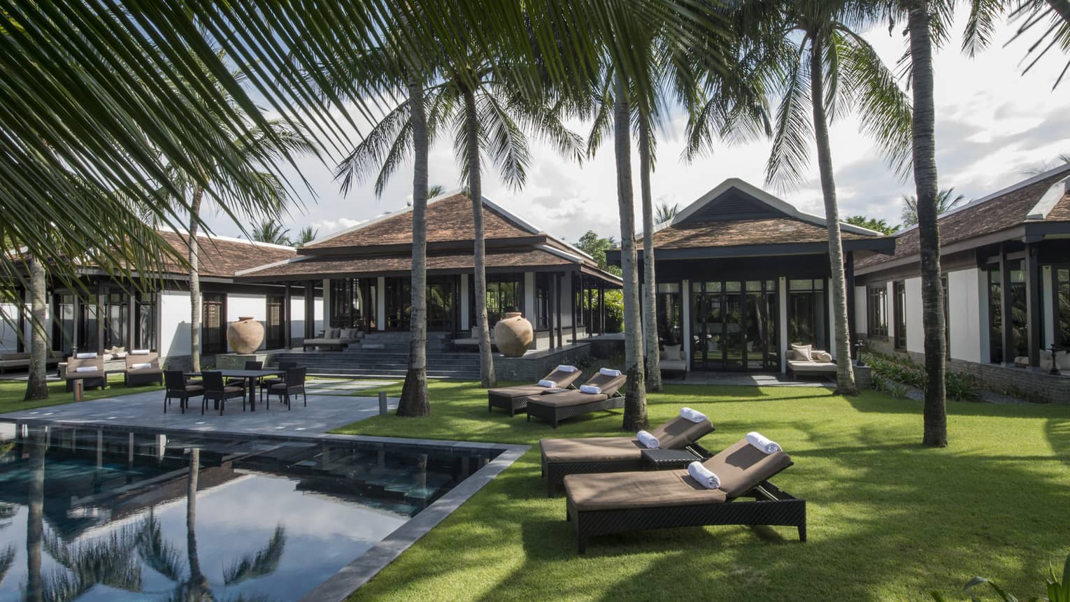 Three-bedroom Hilltop Villas, palm trees, lounge chairs on lawn around outdoor pool