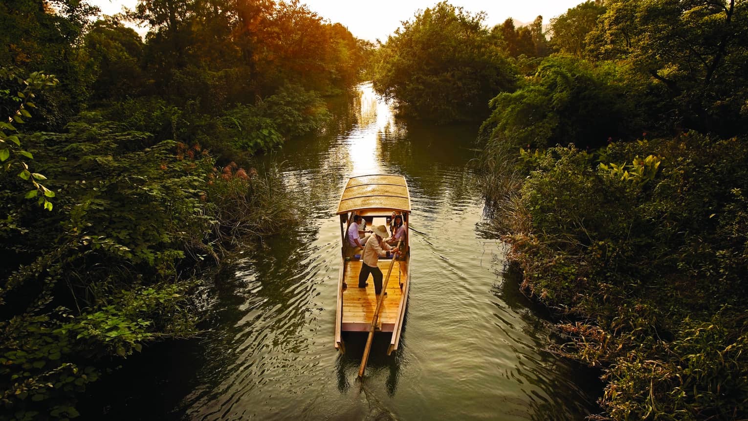 Traditional Chinese wooden boat sails down river in Xixi Wetland National Park