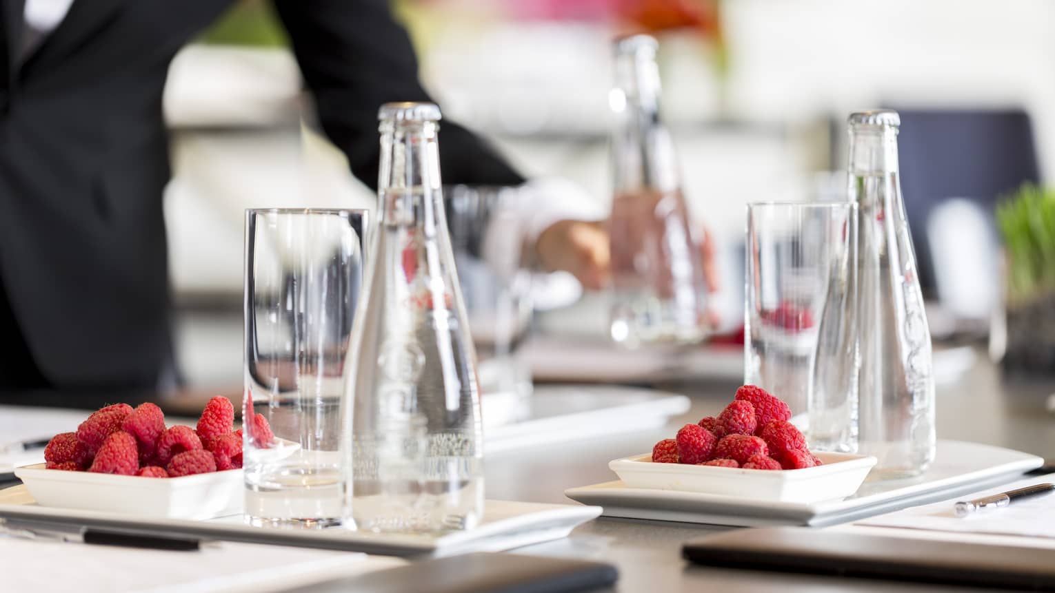 Close-up of tall glass, water bottle on conference meeting table