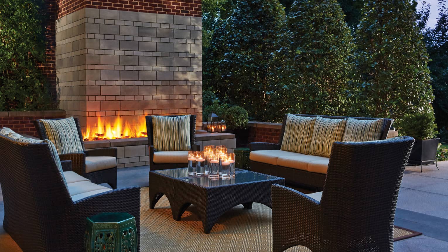 Douglass patio with modern brick fireplace behind outdoor sofas, chairs, table with candles 