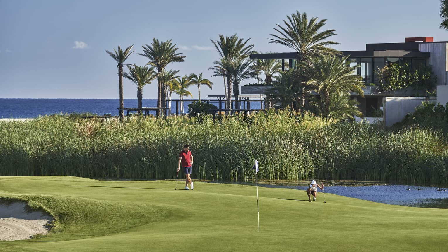Two golfers enjoy a day on the golf course at four seasons los cabos with palm trees and the ocean in the backgound