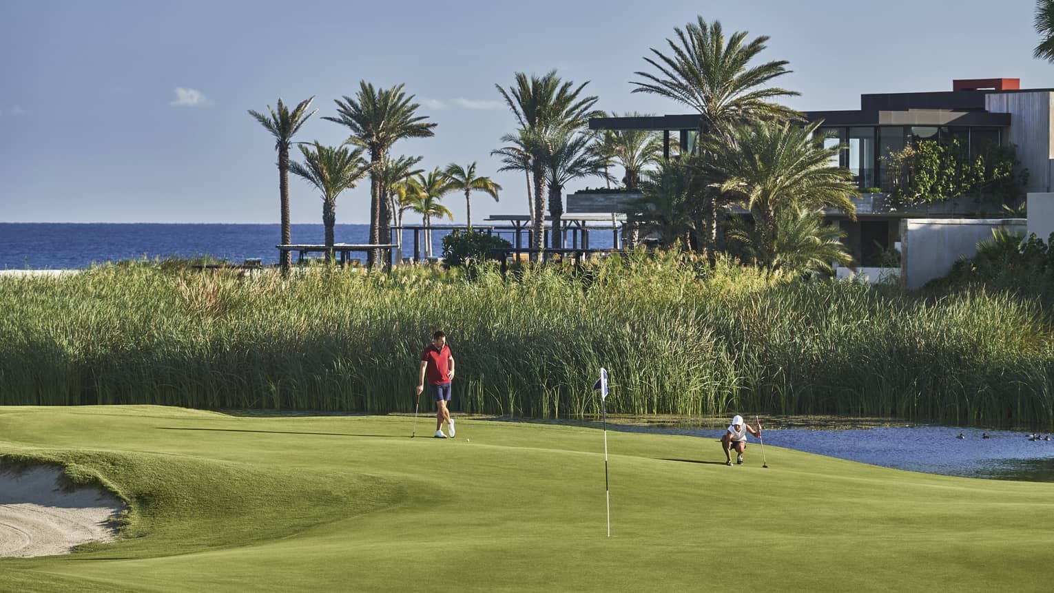 Two golfers enjoy a day on the golf course at four seasons los cabos with palm trees and the ocean in the backgound