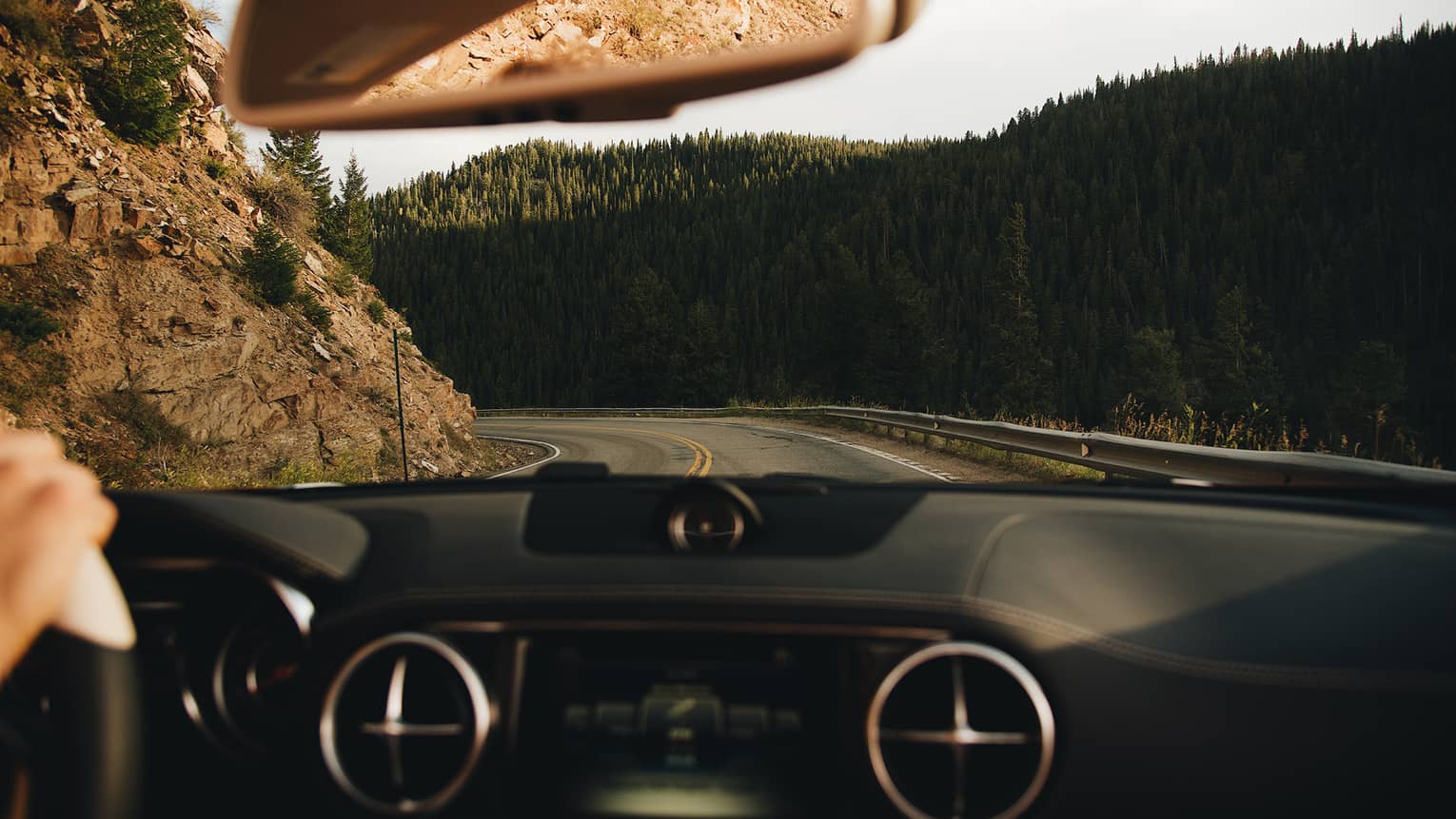 Driver's view over dashboard of Mercedes Benz car to winding mountain road 
