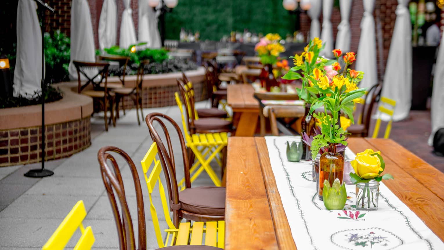 Colourful flowers, chairs, linens around outdoor patio dining tables 