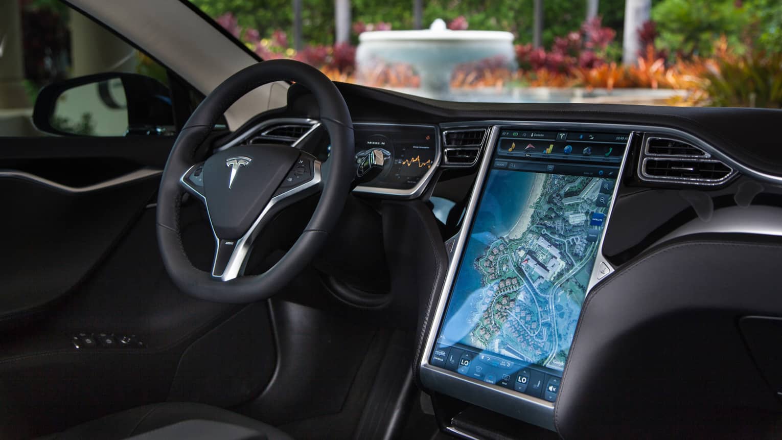 Close-up of car steering wheel and dashboard, tablet touch screen with map
