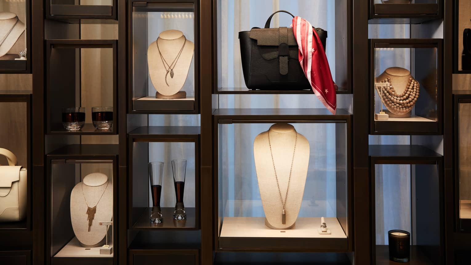 Boutique retail store shelf with designer necklaces, handbag, cocktail glasses 