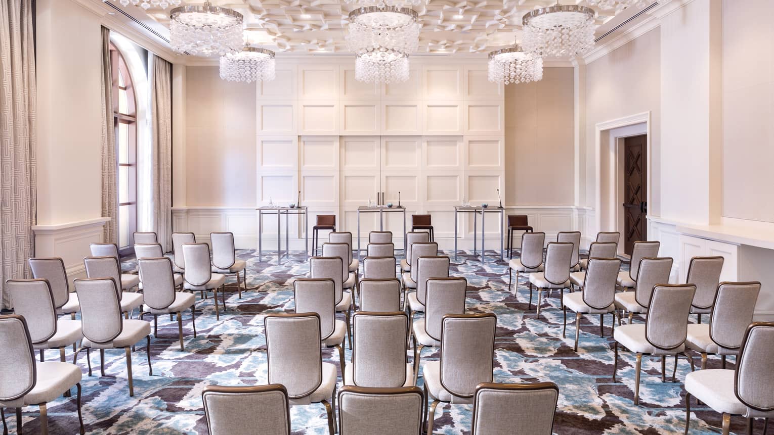 Sunny conference room with rows of chairs facing three speaker tables