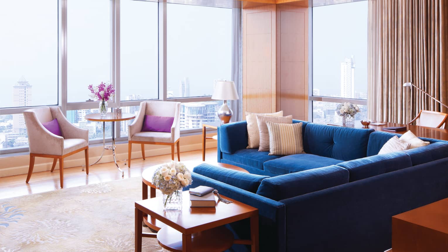Deluxe Suite-Sea room with blue sectional sofa by floor-to-ceiling sunny windows, chairs