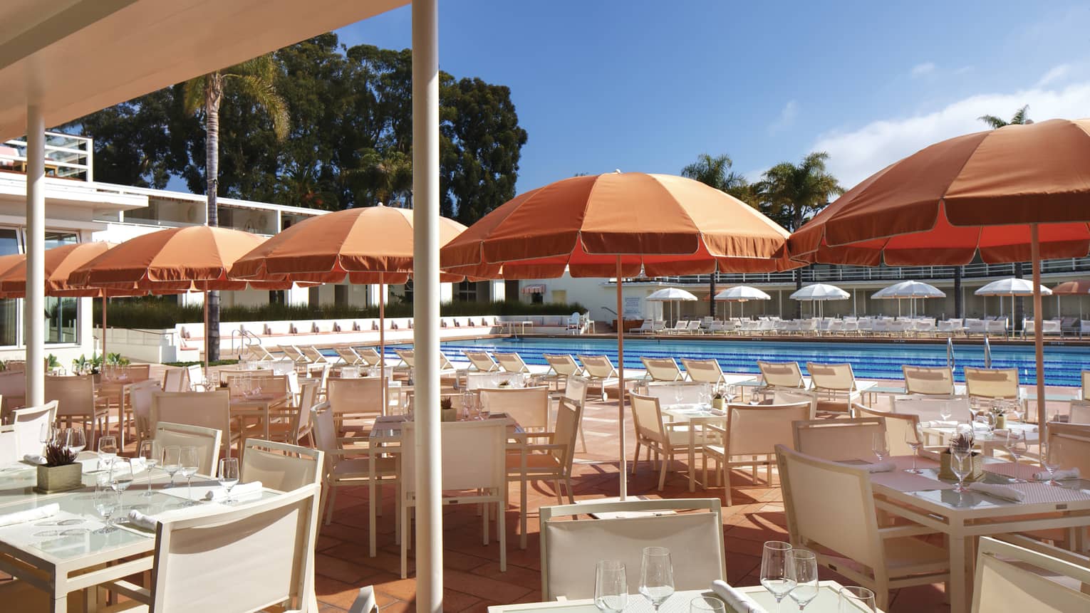 Coral Cafe and Bar patio, orange umbrellas over white dining tables, chairs by pool