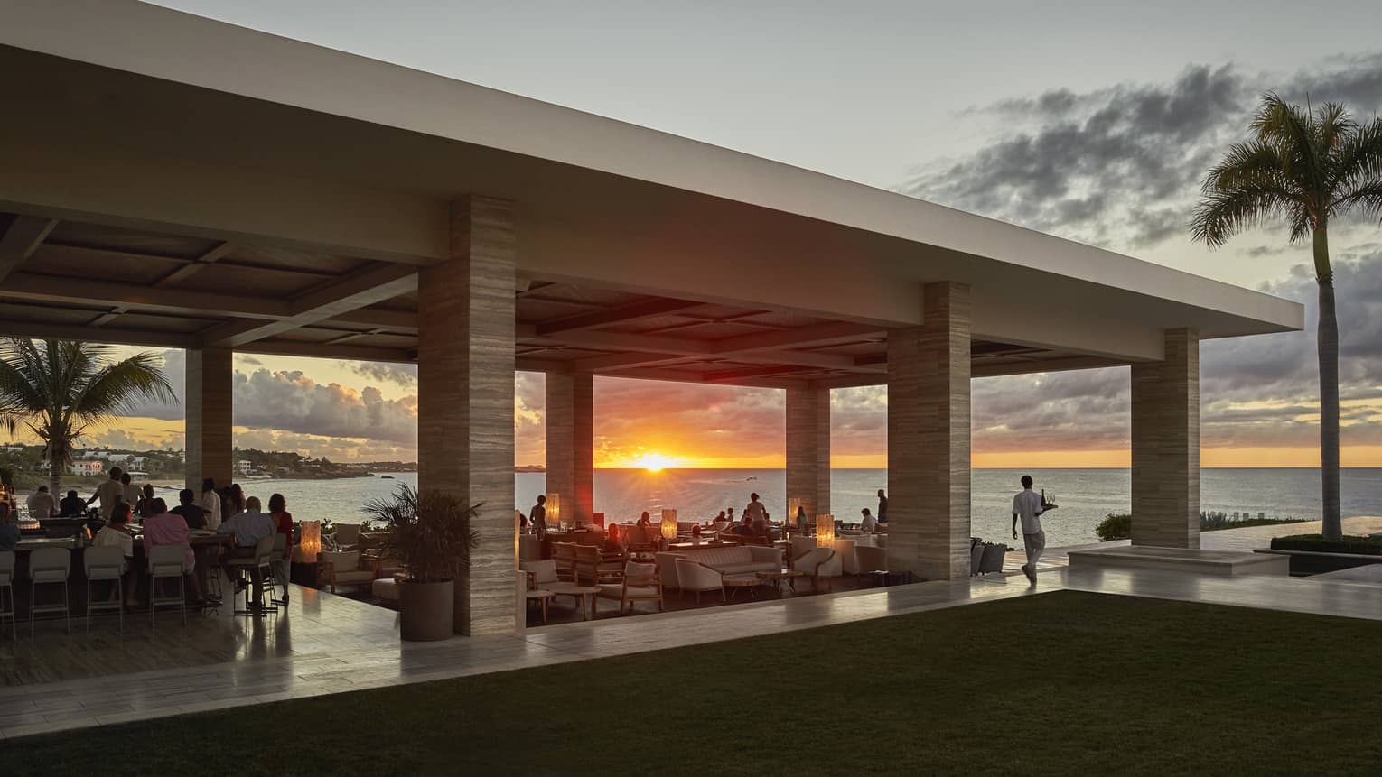 Sunset Lounge poolside bar and dining area at sunset, silhouette of palm tree