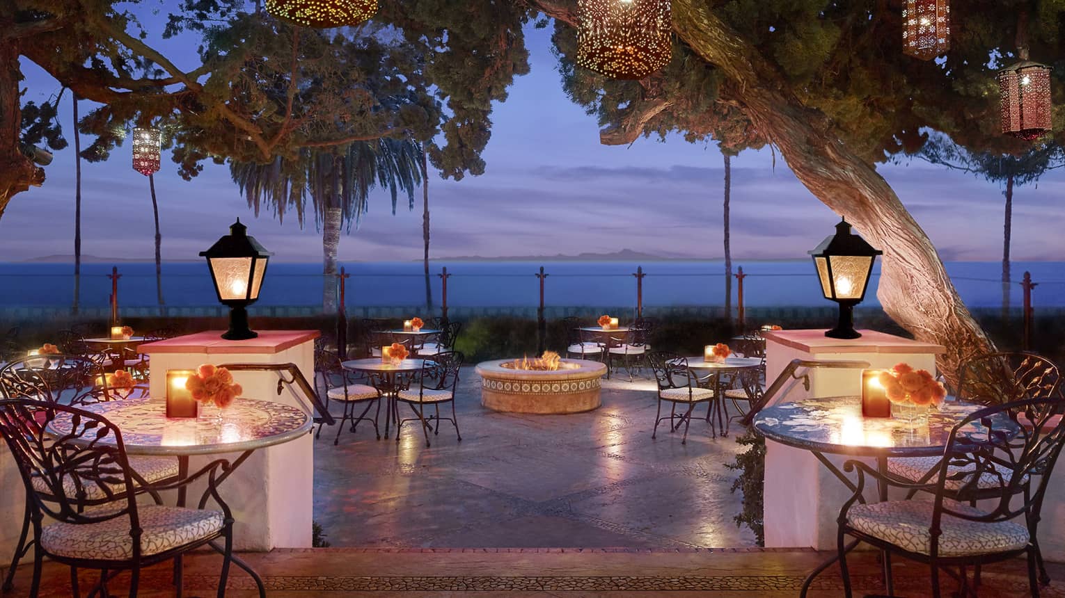 Bella Vista patio at dusk with candle-lit tables under lanterns on posts, hanging from trees
