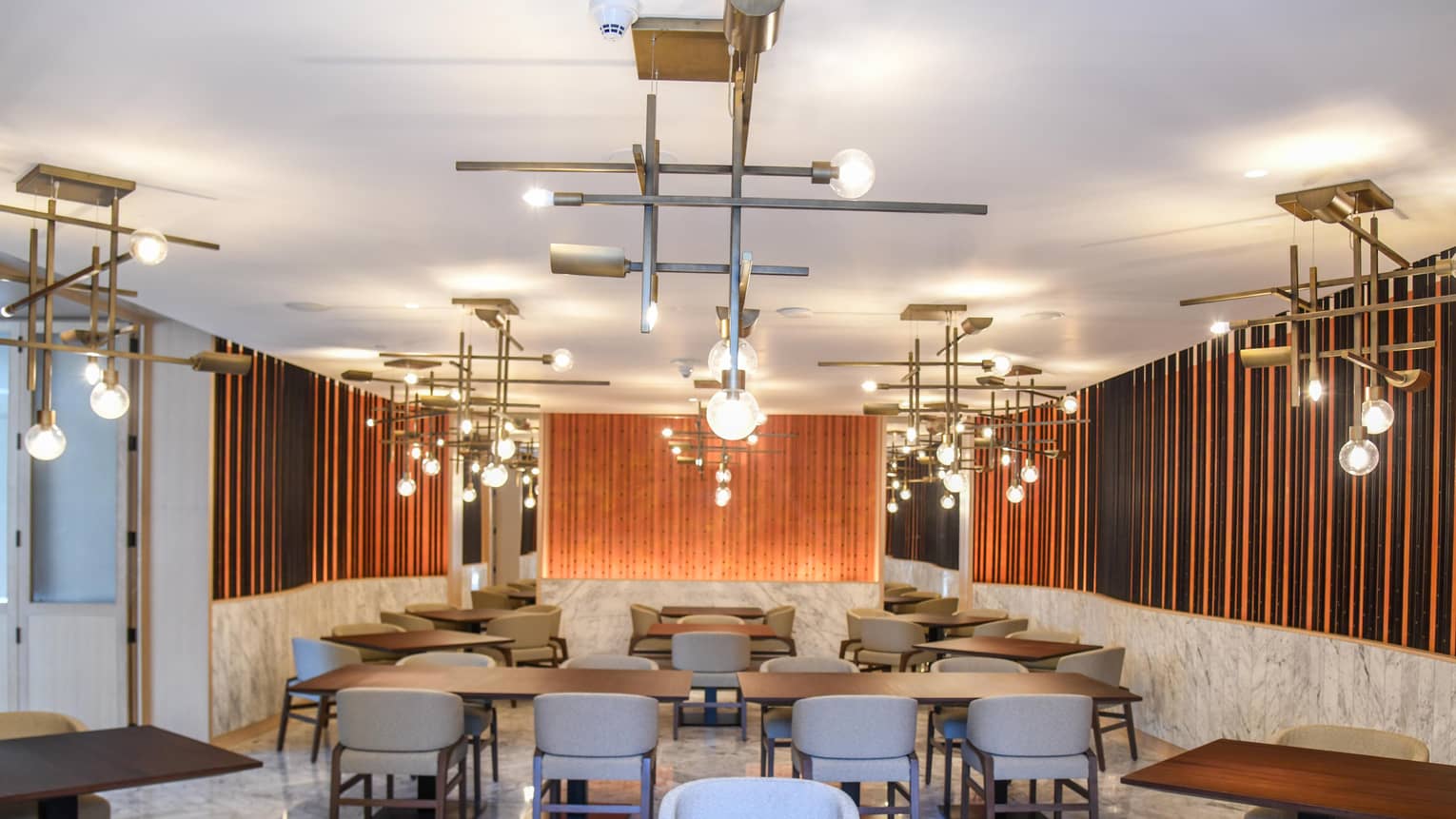 Retro-style globe lights over tables, chairs in modern CUR8 dining room