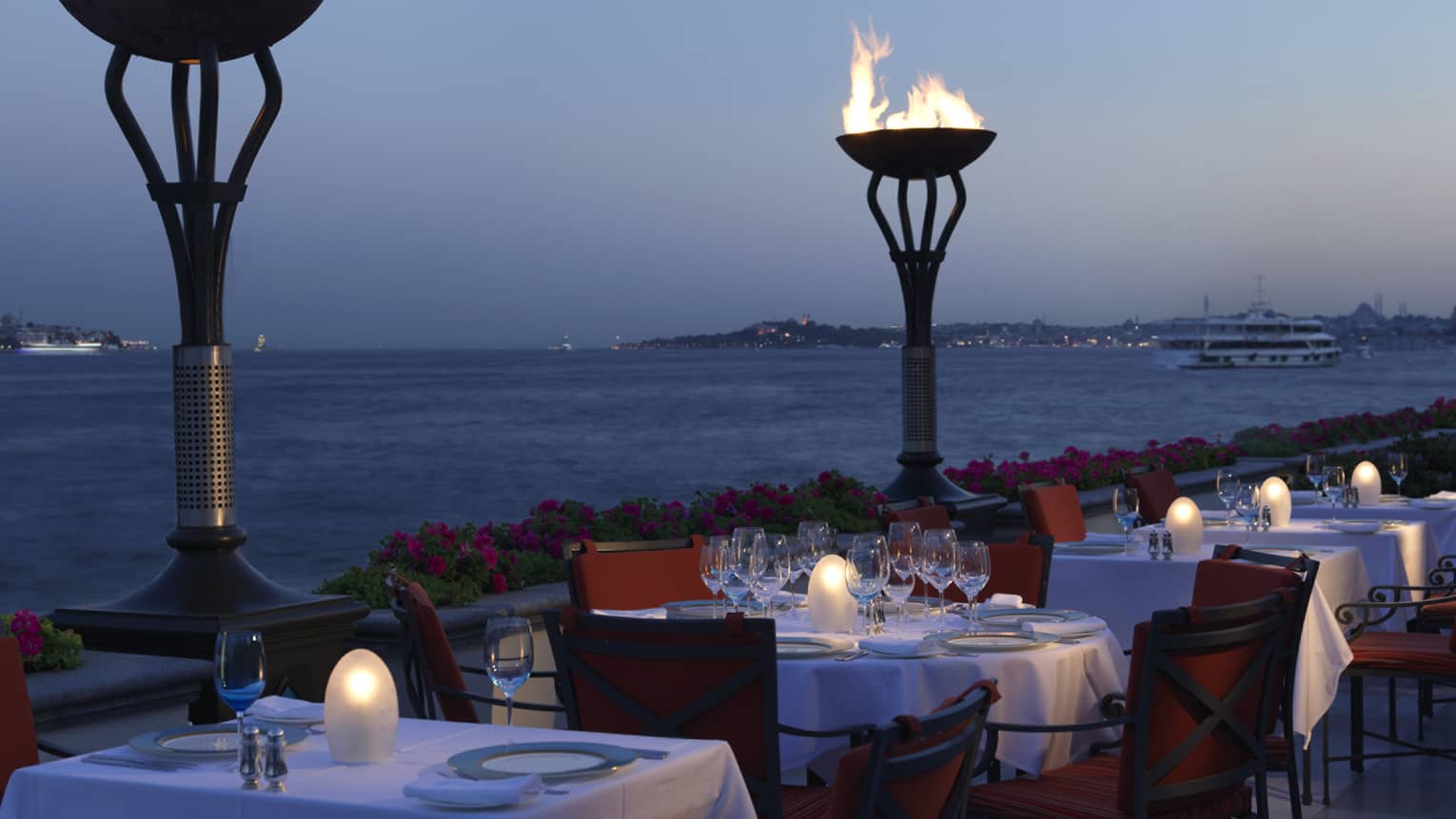Large torches over dining tables on Aqua Terrace at dusk
