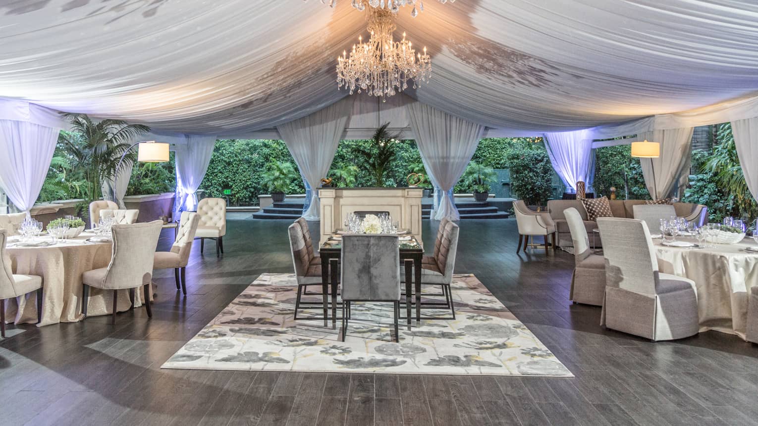 The Pavilion outdoor event space with dining tables under white fabric tent, crystal chandelier 