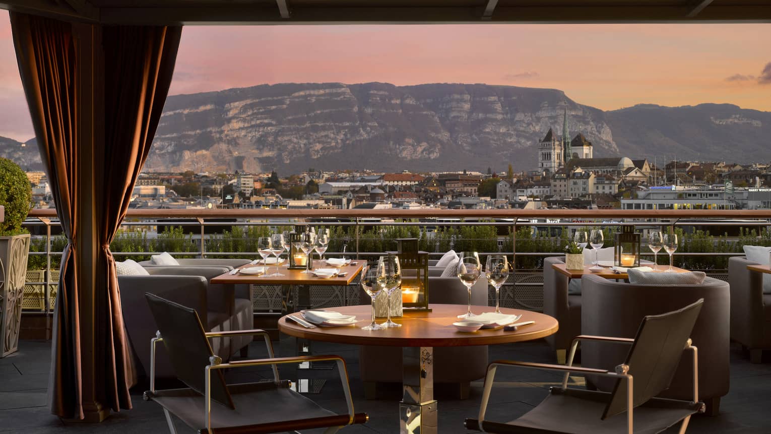 Dining tables on patio with velvet curtains looking out at sunset, mountains