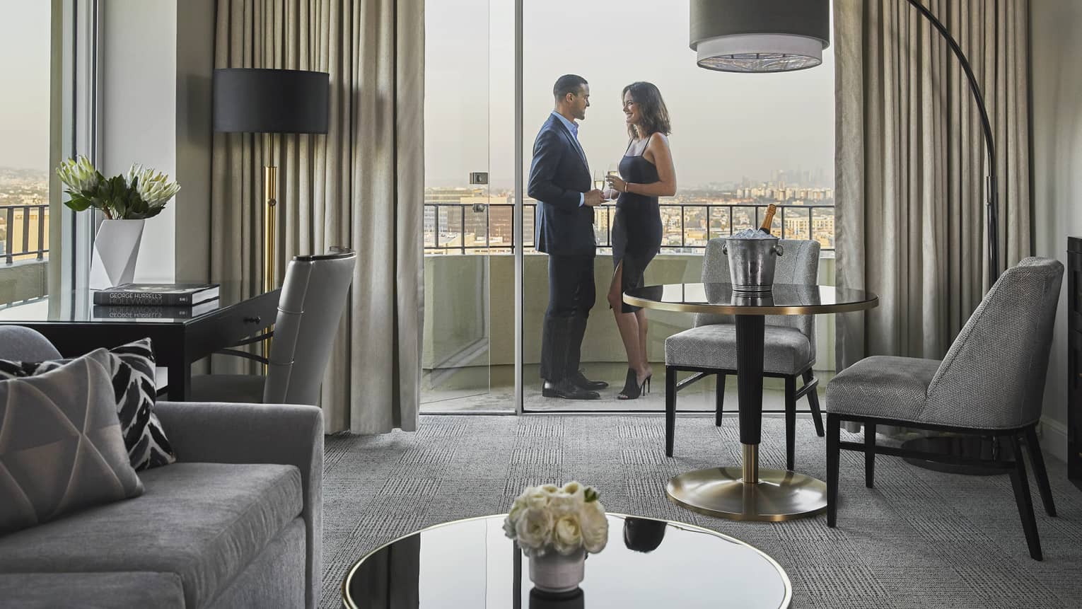 Couple wearing formal attire stand on hotel suite patio off seating area