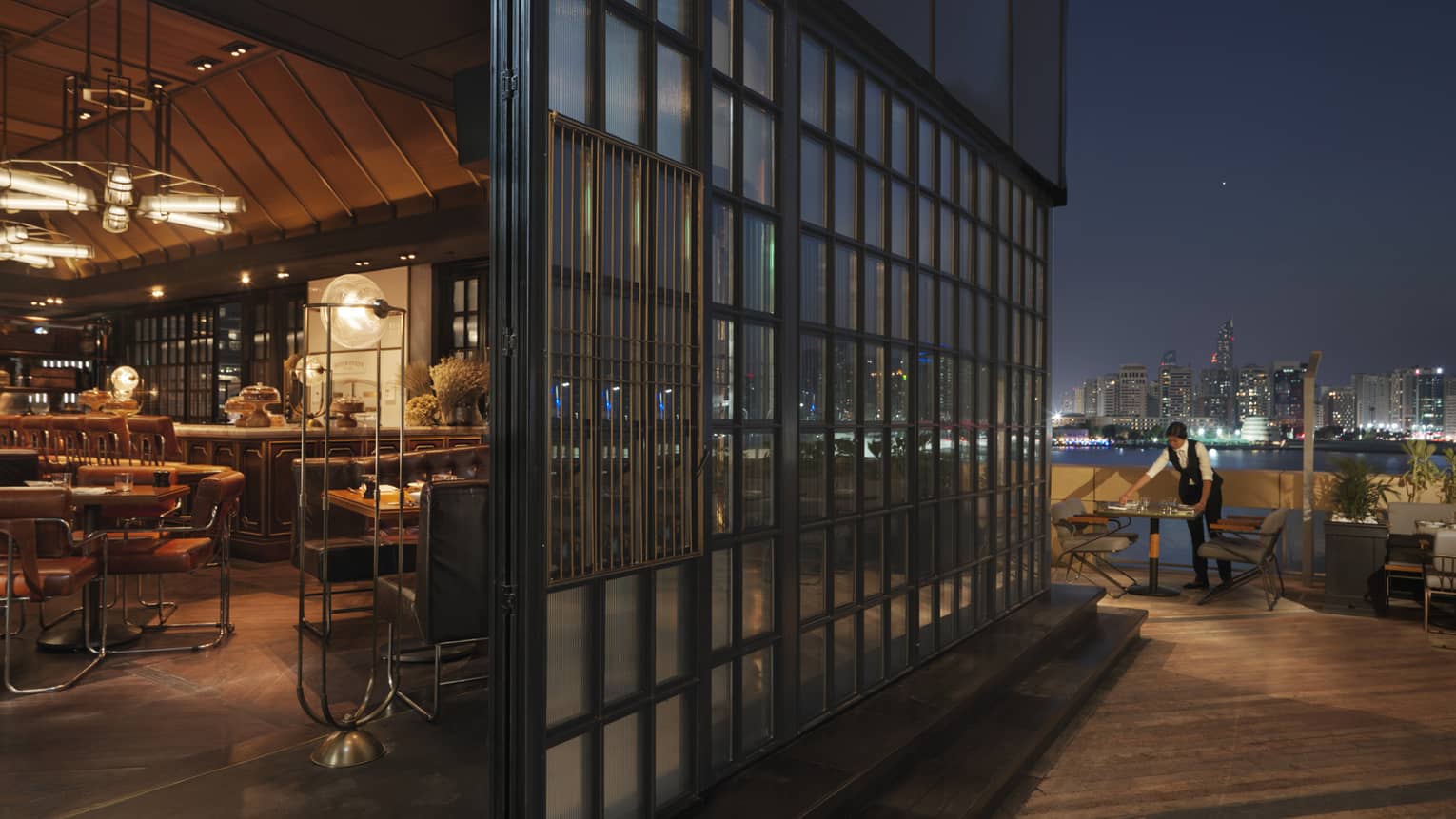 Looking into dimly-lit Al Capone at Butcher & Still dining room past glass wall from patio at dusk