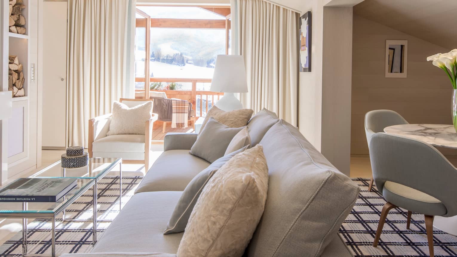Hotel suite with dining table, white sofa across from modern white fireplace 