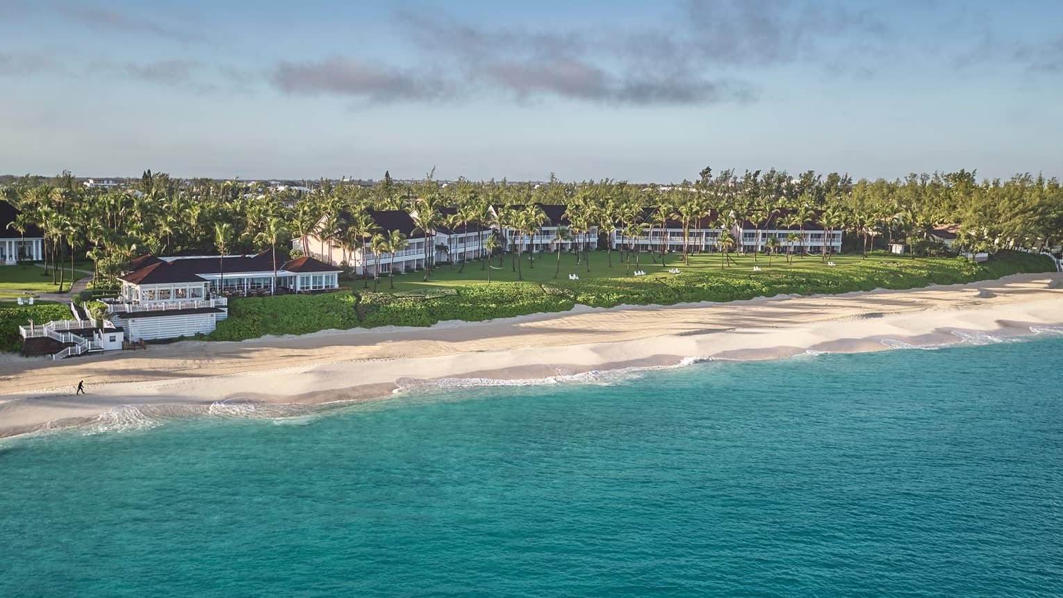 Resort buildings behind long, white sand beach across turquoise ocean