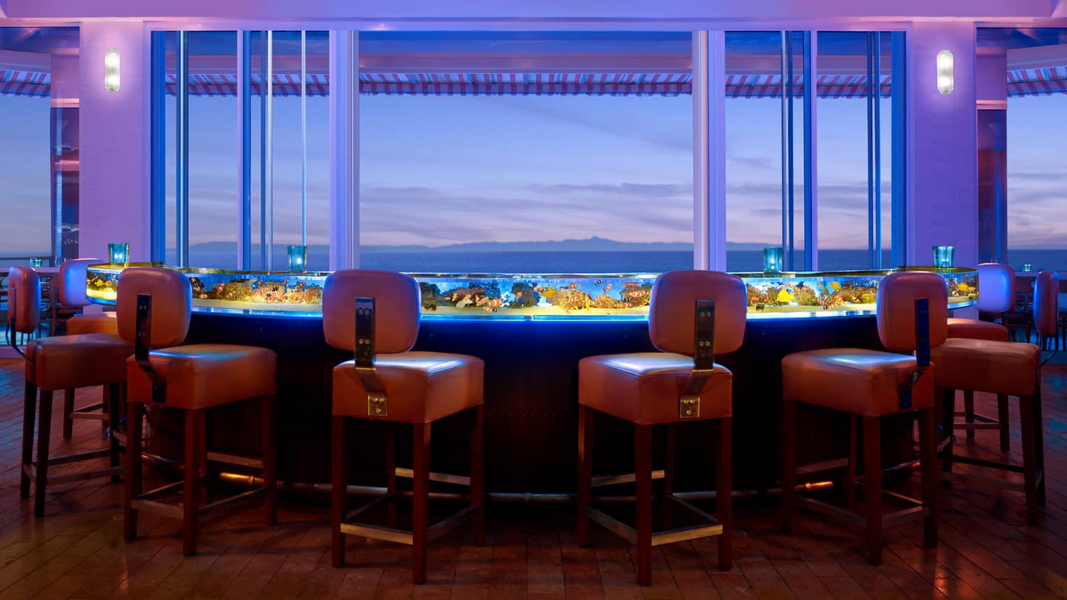 Orange stool around glowing Coral Reef glass bar filled with water, tropical fish
