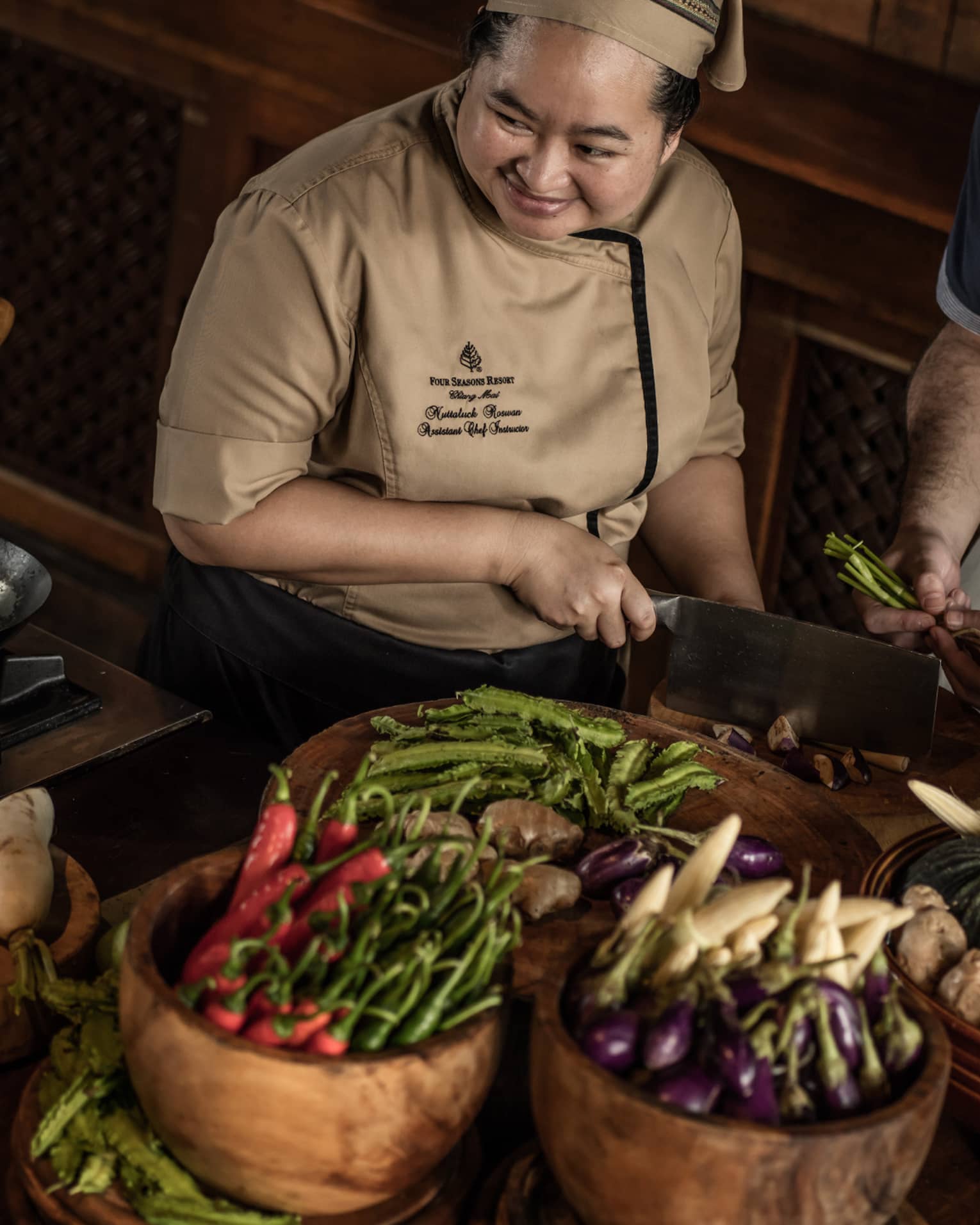 Chef chops mushrooms in front of couple, bamboo baskets with vegetables