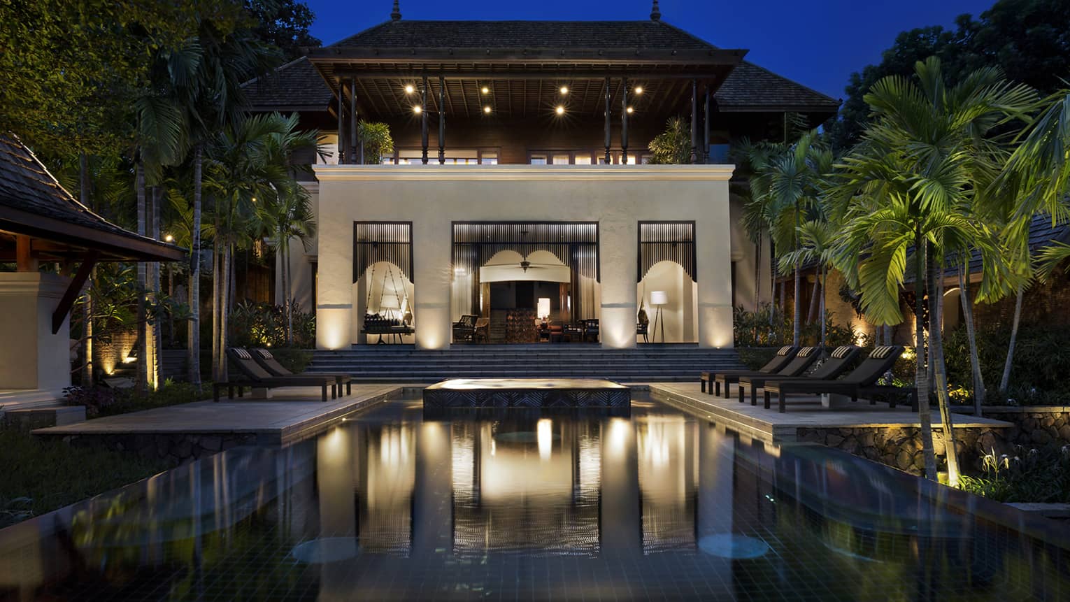 Large Four-Bedroom Residence Villa at night with lights, outdoor pool and palms 