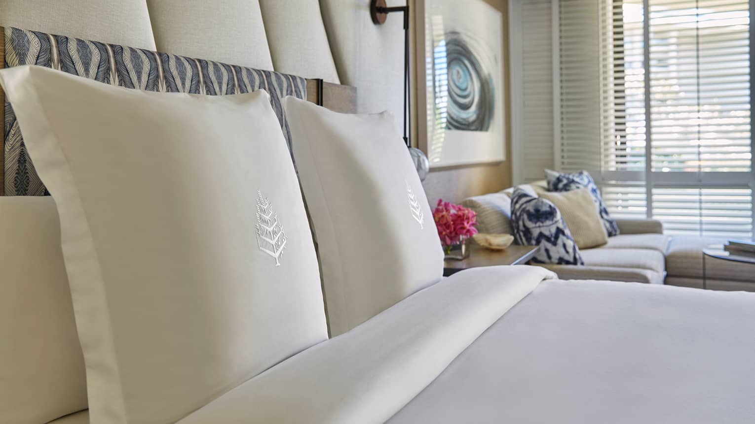 Garden-View suite pillows and bed linens with Four Seasons logo, white sofa and blue pillows in background