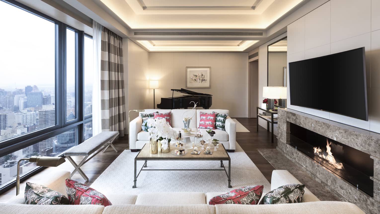Gotham Suite sofas, tables with trays of sweets between floor-to-ceiling window, large TV