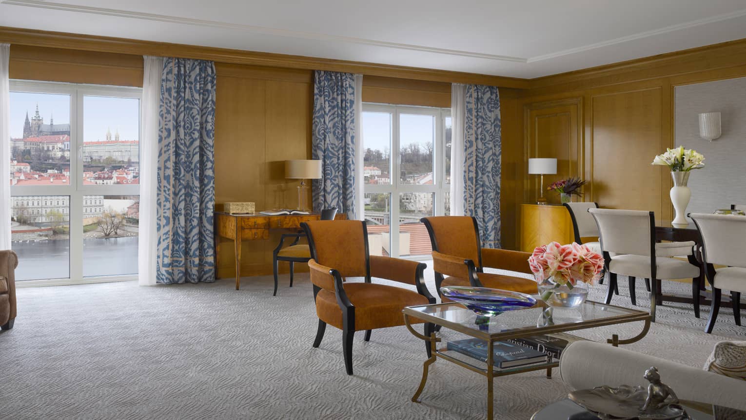 Spacious Premier Suite seating area with tan chairs, sunny windows