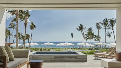 Pacific Suite open to wall to patio with stone plunge pool, lounge chairs, ocean views