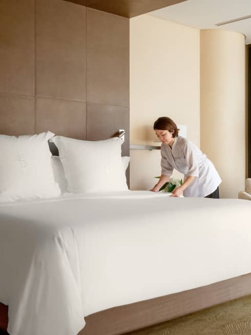 Hotel staff makes bed in Deluxe City View