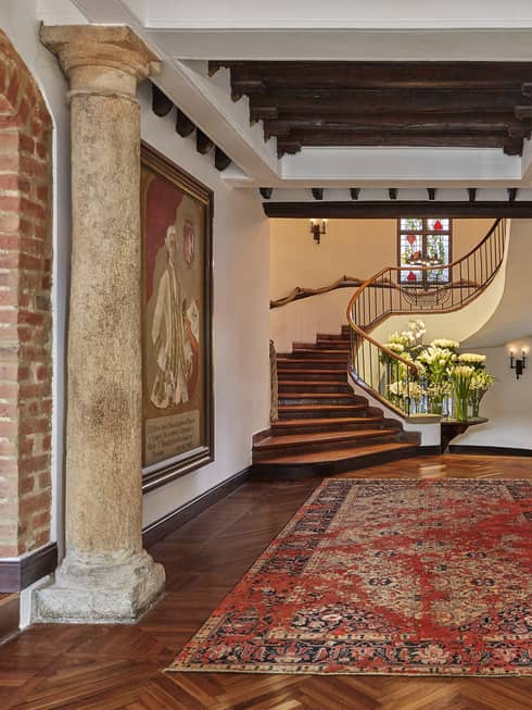 Hotel lobby with stone pillars, carpet and paintings in front of spiral staircase