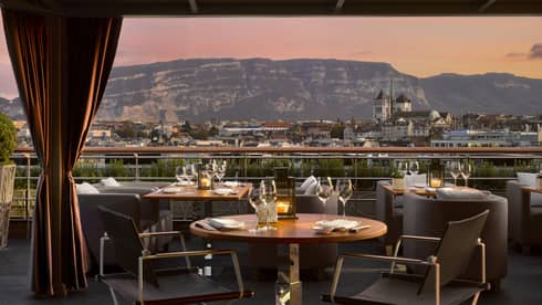 Dining tables on patio with velvet curtains looking out at sunset, mountains