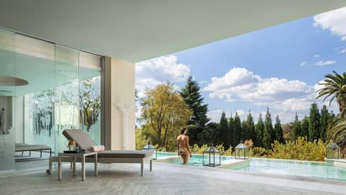 Woman walks into outdoor plunge pool in front of covered patio with chaise 