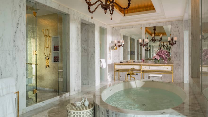 Royal Suite white marble master bathroom with circular spa tub, stand-up shower