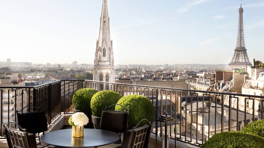 Gold vase on black patio table and chairs on sunny rooftop patio overlooking Paris